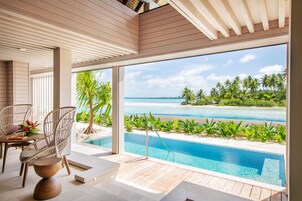 A modern indoor pool area with a view of a beach and ocean.