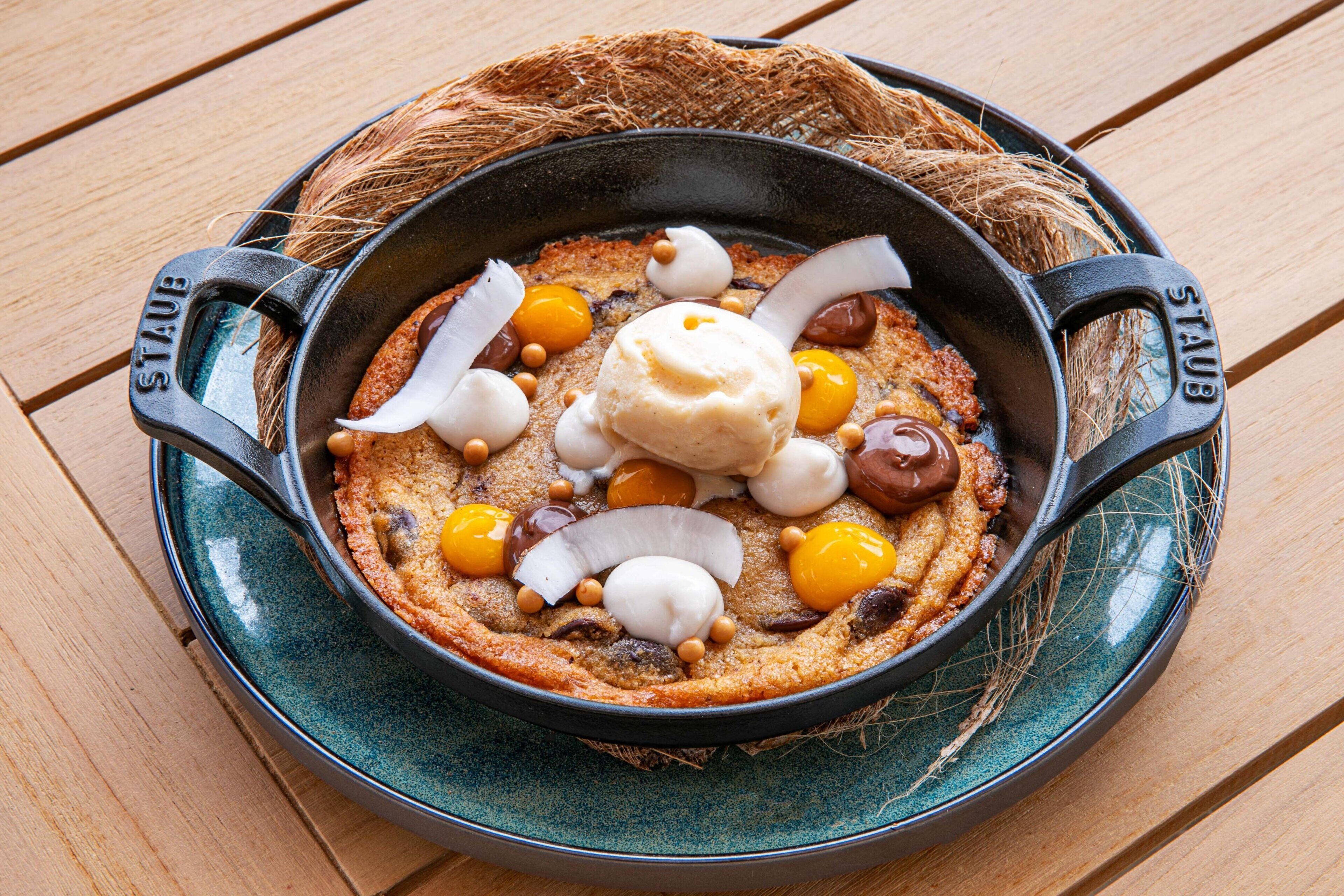 Ein Dessert in einer gusseisernen Pfanne auf einem rustikalen Holztisch.