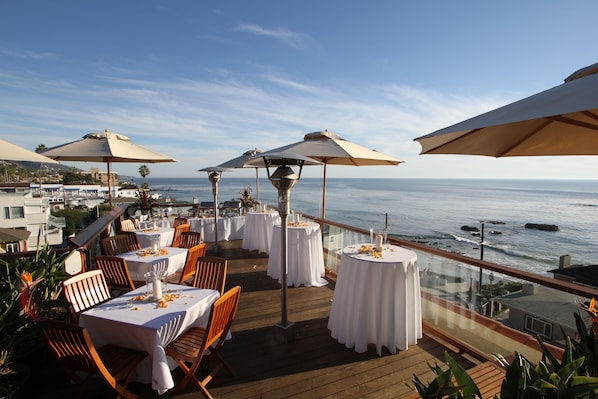 Un área de comedor frente al mar, con mesas dispuestas para los comensales.