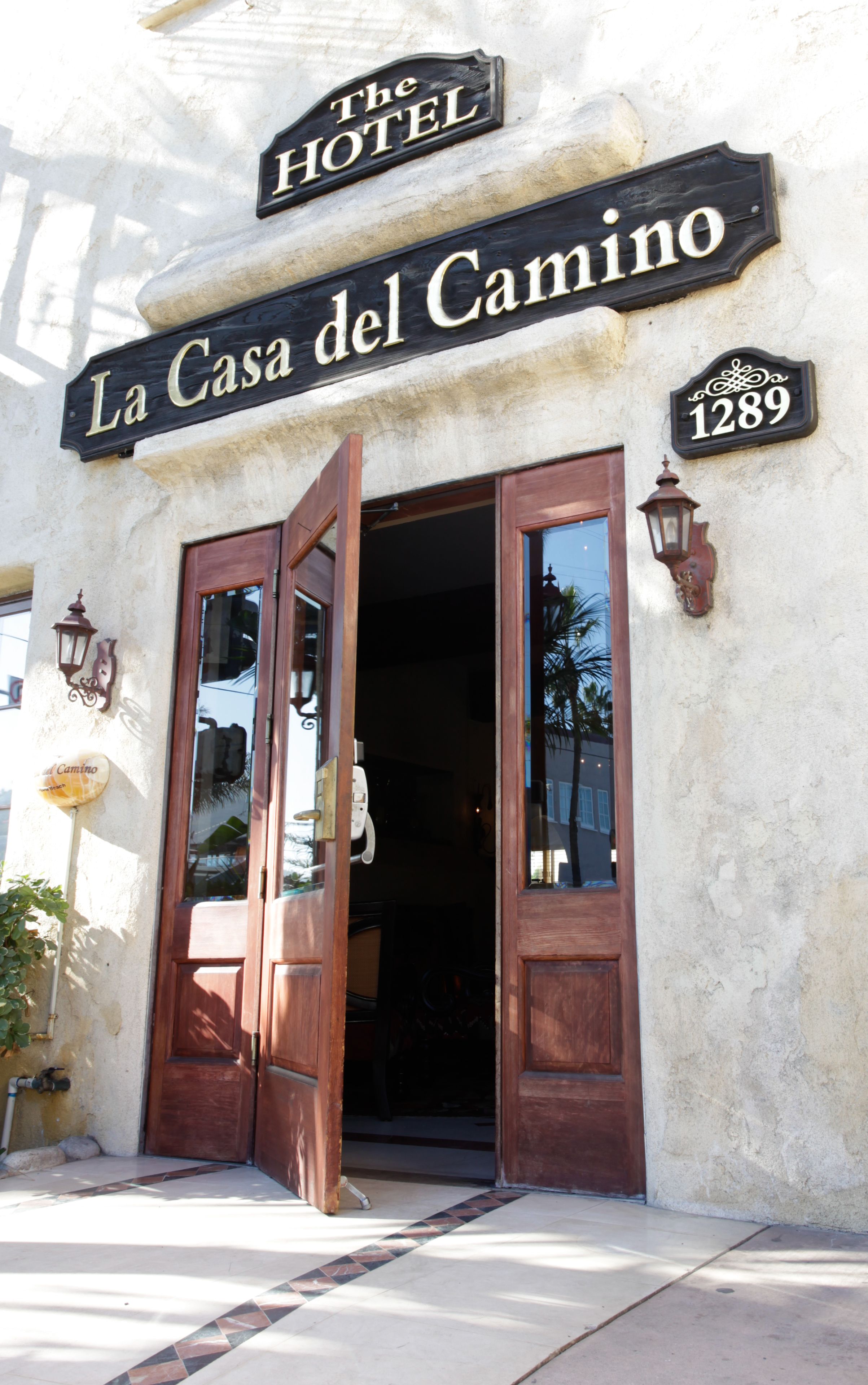 The entrance to La Casa del Camino hotel with wooden doors and a sign above.