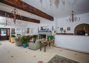 A spacious living room with a fireplace, multiple seating areas, and a high ceiling with exposed beams.