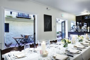 A dining area with a long table set for a meal, a large candle centerpiece, and a view of the outdoor patio.