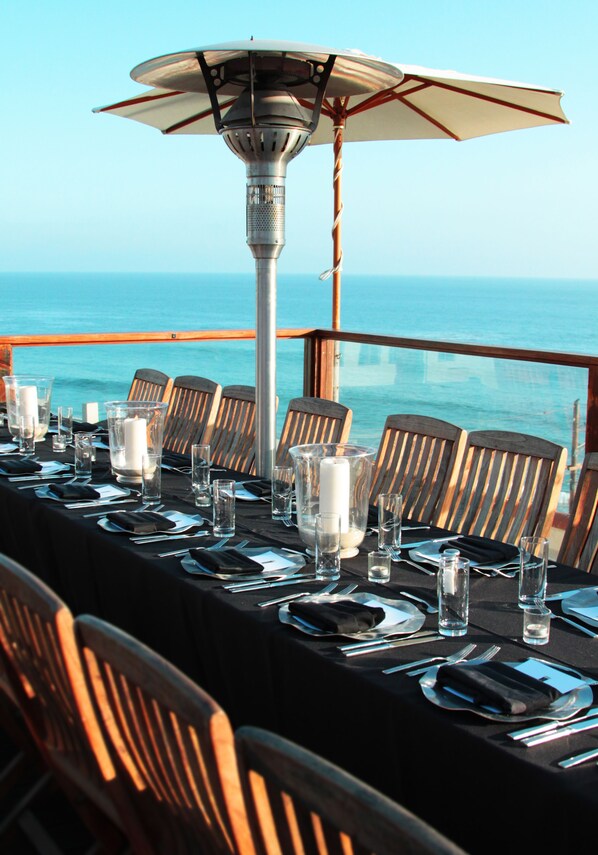 A table set for dining with a view of the ocean, a table lamp, and wooden chairs. - La Casa del Camino (Laguna Beach)