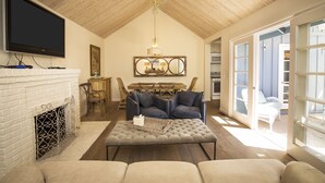 Una sala de estar con chimenea, televisor, candelabro y un comedor con mesa y sillas.