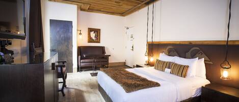 A bedroom with a wooden ceiling, a large bed with a fluffy blanket, bedside lamps, and a wooden nightstand.