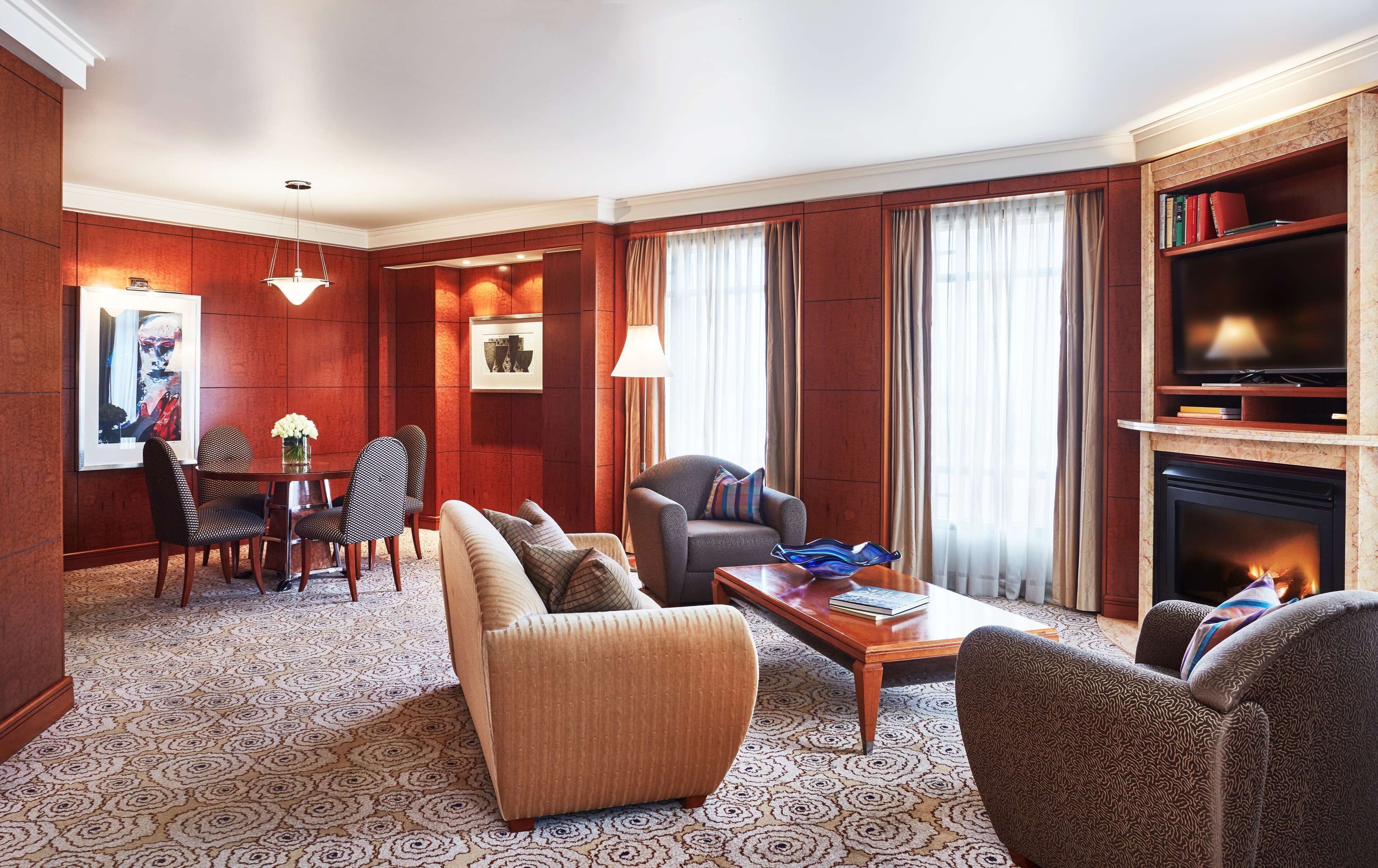 A well-appointed living room with a sofa, armchairs, a coffee table, a fireplace, a television, and a bookshelf.