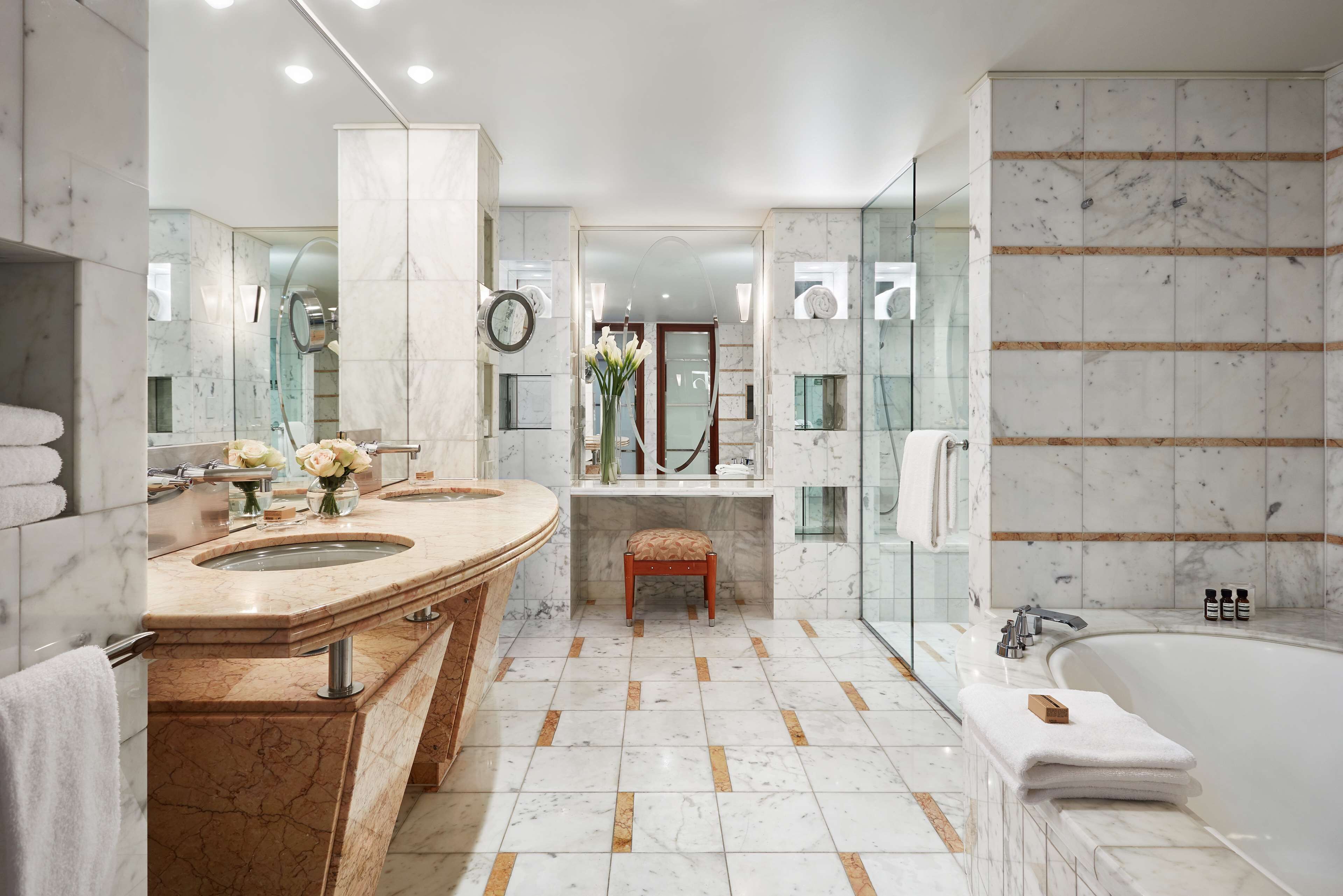 Une salle de bain moderne dotée d’un meuble-lavabo à deux vasques, d’une baignoire sur pieds et d’une douche séparée par des parois en verre.