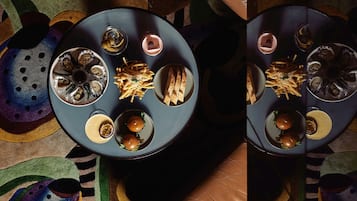 Una mesa de comedor con diferentes platos, entre ellos ostras, papas fritas y hamburguesas.