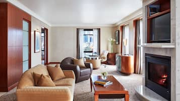 A spacious living room with a fireplace, leather sofas, a coffee table, and a large TV.