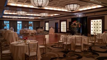 Un salón de banquetes con mesas redondas, sillas, candelabros y decorados con motivos de estrellas.