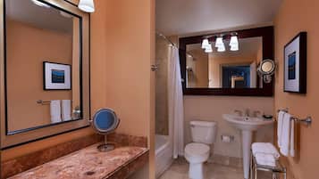 A bathroom with a marble countertop, a sink, a toilet, and a shower.