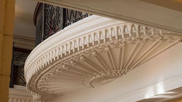 A detailed ceiling with ornate carvings and a balcony with wrought iron railings.