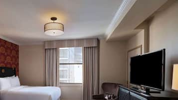 A hotel room with two beds, a television, and a window with curtains.