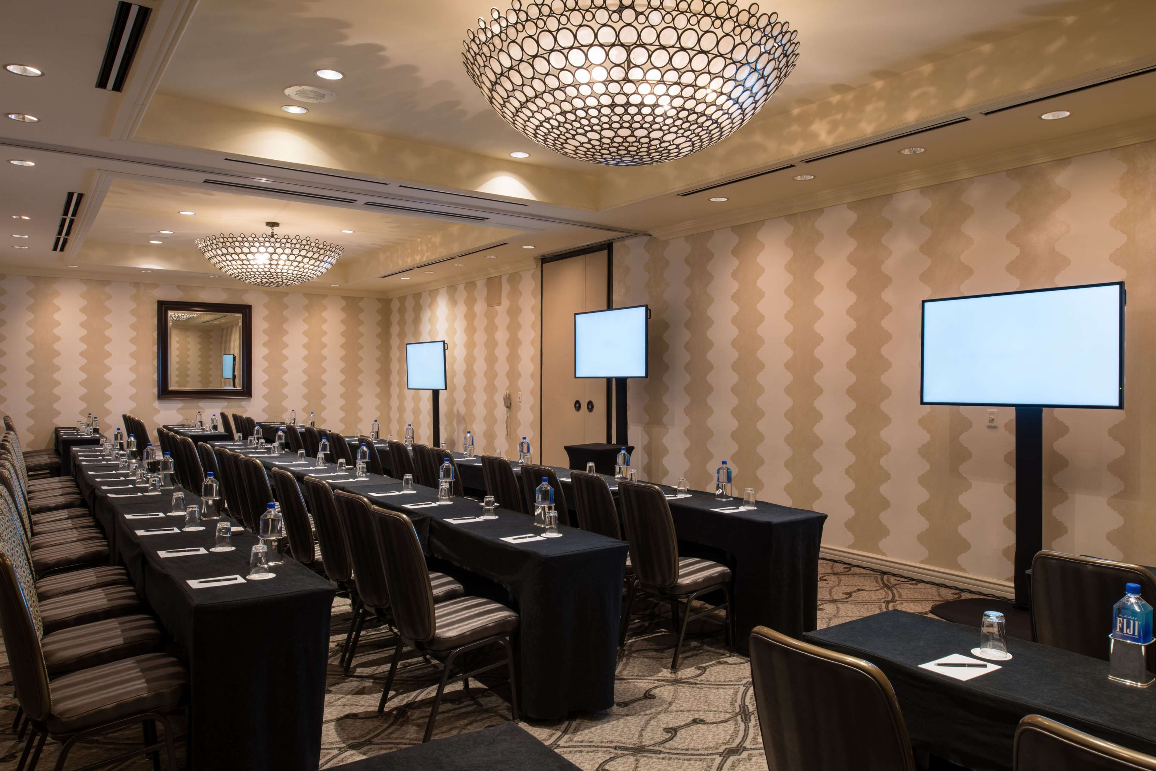 A conference room with long tables, chairs, and a large chandelier.