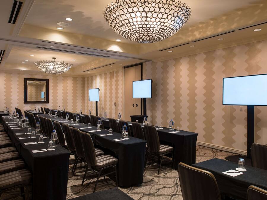 A conference room with long tables, chairs, and a large chandelier.