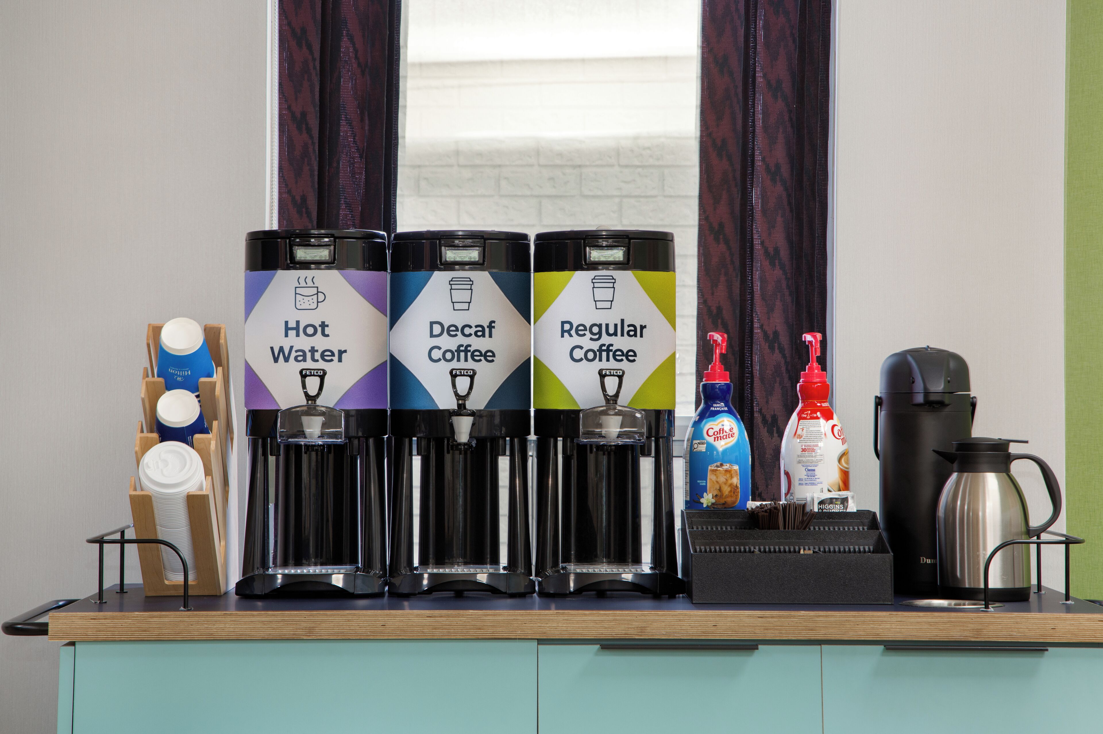 A coffee station with hot water, decaf coffee, and regular coffee dispensers.