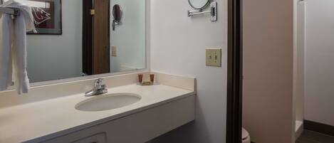 A bathroom with a white sink, a mirror, a towel rack, and a toilet.