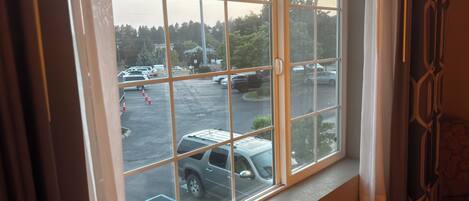 A view through a window with a view of a parking lot and a building in the background.