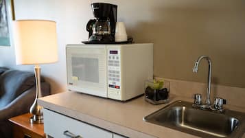 Une petite cuisine équipée d’un four à micro-ondes, d’une machine à café et d’un évier.