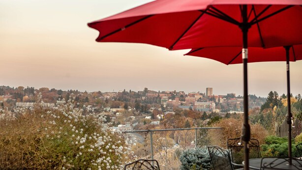 A patio with red umbrellas overlooking a cityscape.