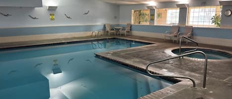 Una piscina sin indicaciones de buceo, un área de descanso con sillas y un letrero en la pared.