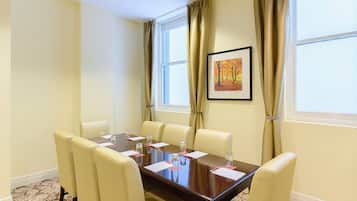 A conference room with a wooden table, six chairs, and a framed painting on the wall.