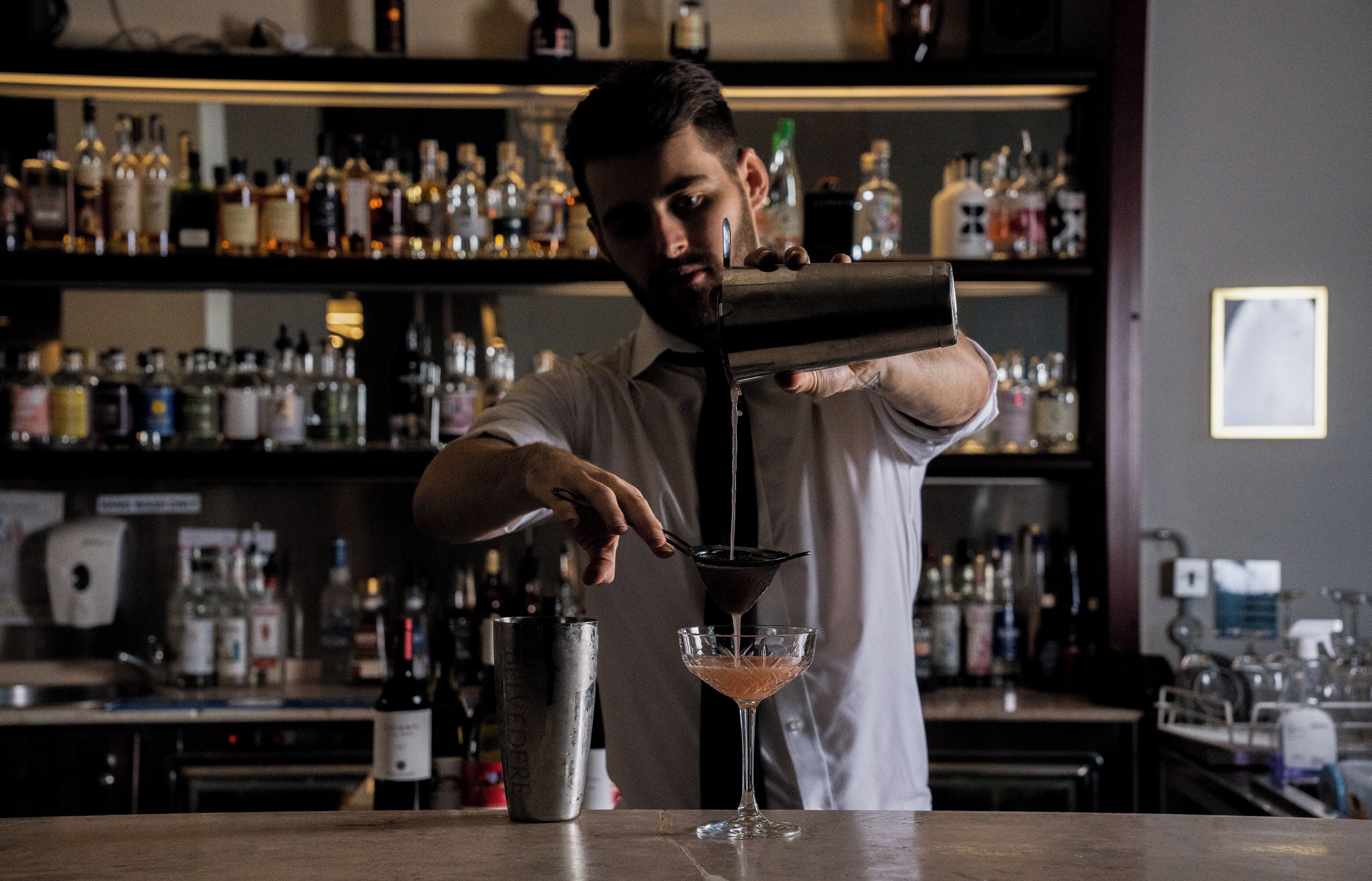 A bartender pouring a drink into a martini glass.