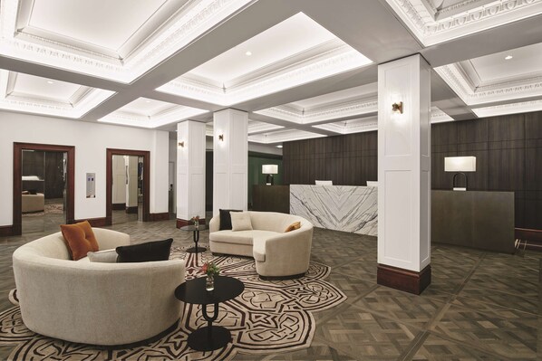 A spacious lobby with a high ceiling, modern lighting, and a reception desk.