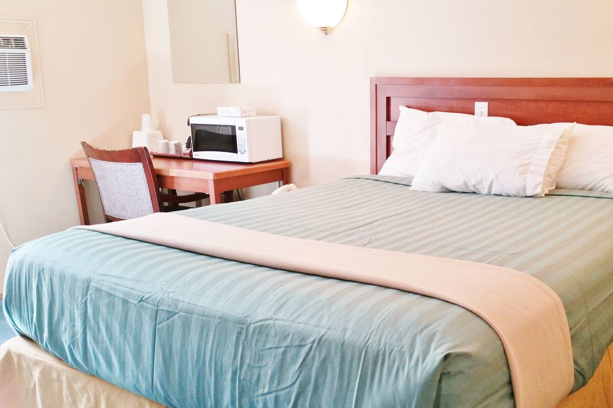Une chambre d’hôtel comprenant un lit, un bureau avec un micro-ondes et une chaise.