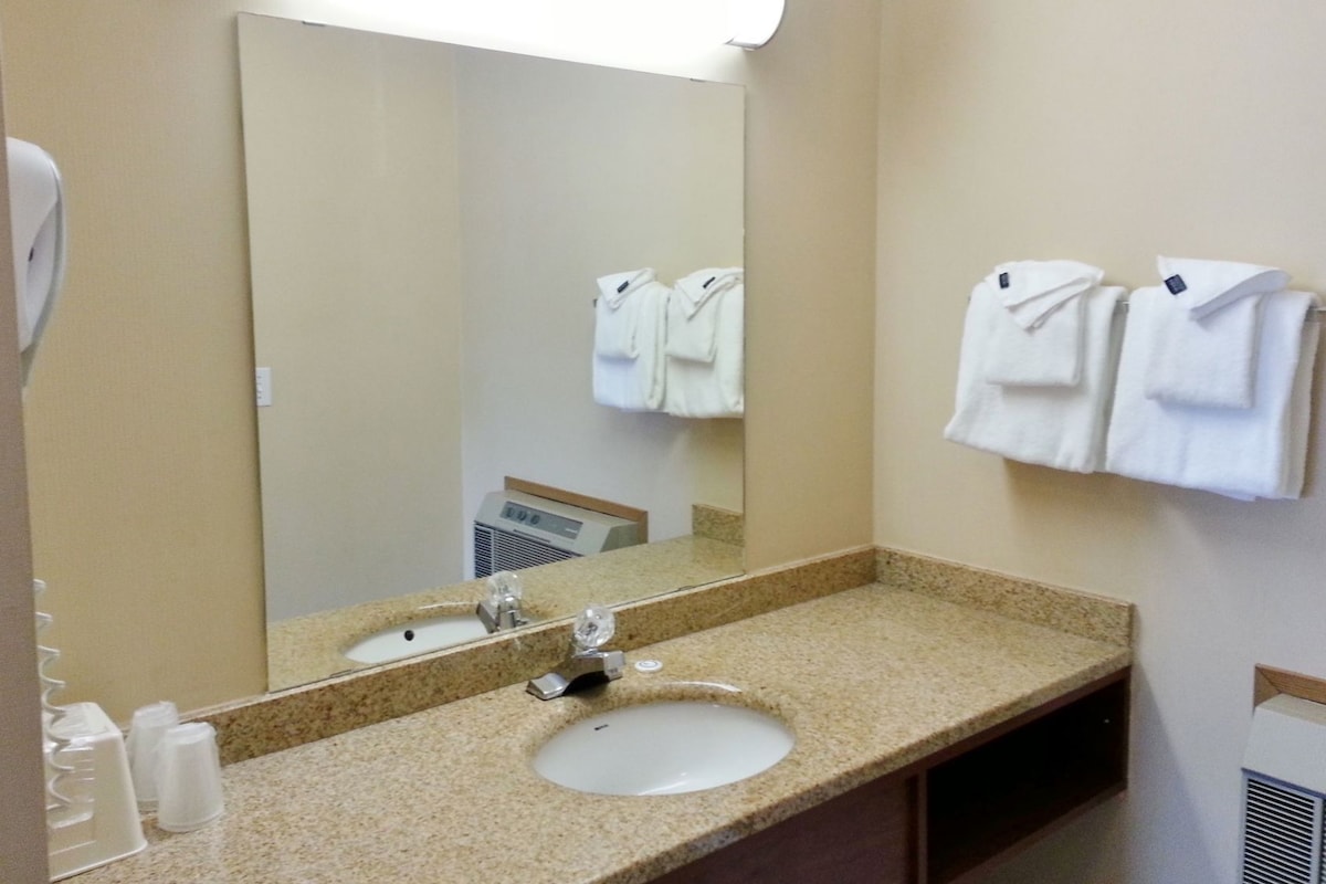 A bathroom with a sink, mirror, towel rack, and a wall-mounted heater.