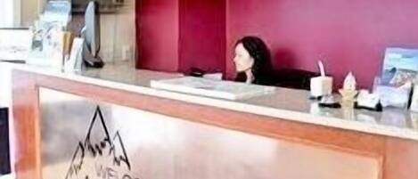 A reception desk with a sign reading "Welcome to the Alpine Motel".