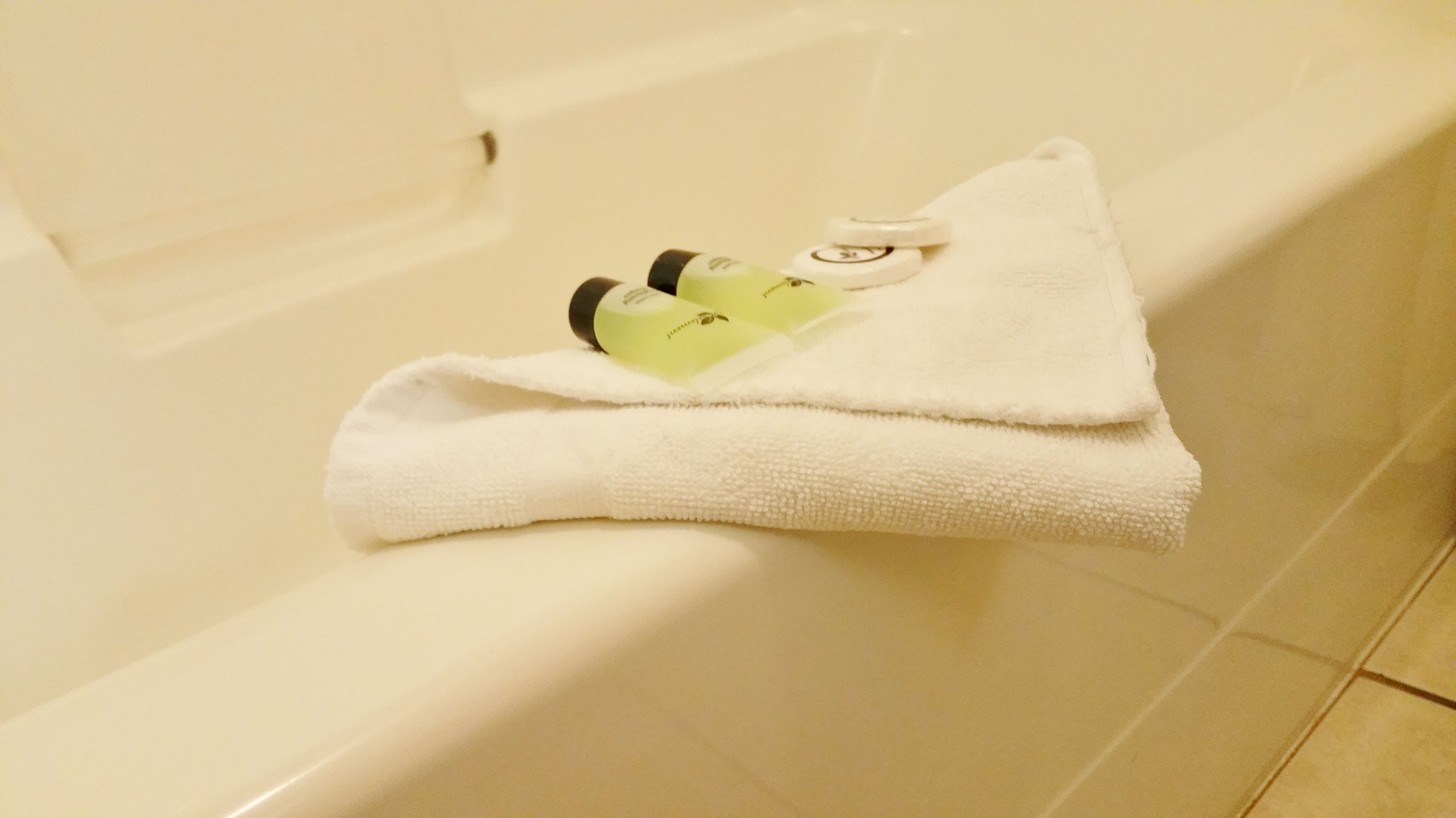 Una toalla blanca doblada sobre una bañera con un par de zapatillas encima.