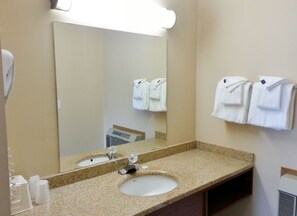 A bathroom with a sink, mirror, and towel rack.
