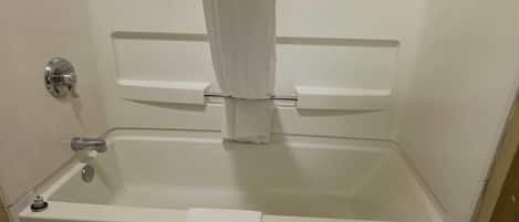 A white bathtub with a shower curtain, a towel, and a faucet.