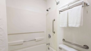 A bathroom with a white bathtub, grab bars, and a towel rack. - Super 8 by Wyndham Coshocton Roscoe Village (Coshocton)
