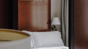A hotel room with a bed, a lamp, a painting on the wall, and a window with curtains.