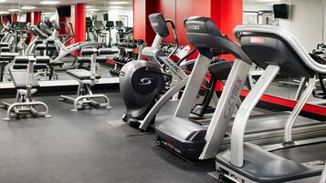 A gym with multiple treadmills, weight machines, and dumbbells.