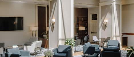 A spacious lobby with a high ceiling and skylight, featuring modern furniture and a central seating area.