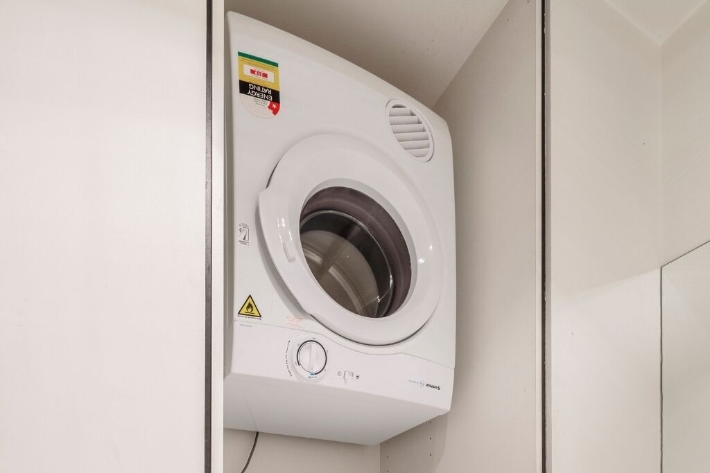 Un lave-linge à chargement frontal dans une buanderie aux murs blancs.