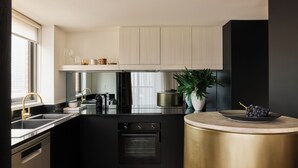 A modern kitchen with black cabinetry, stainless steel appliances, and a wooden floor.