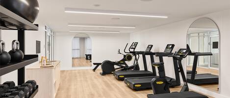 Ein modernes Fitnessstudio mit Laufbändern, Rudergeräten und Gewichten.