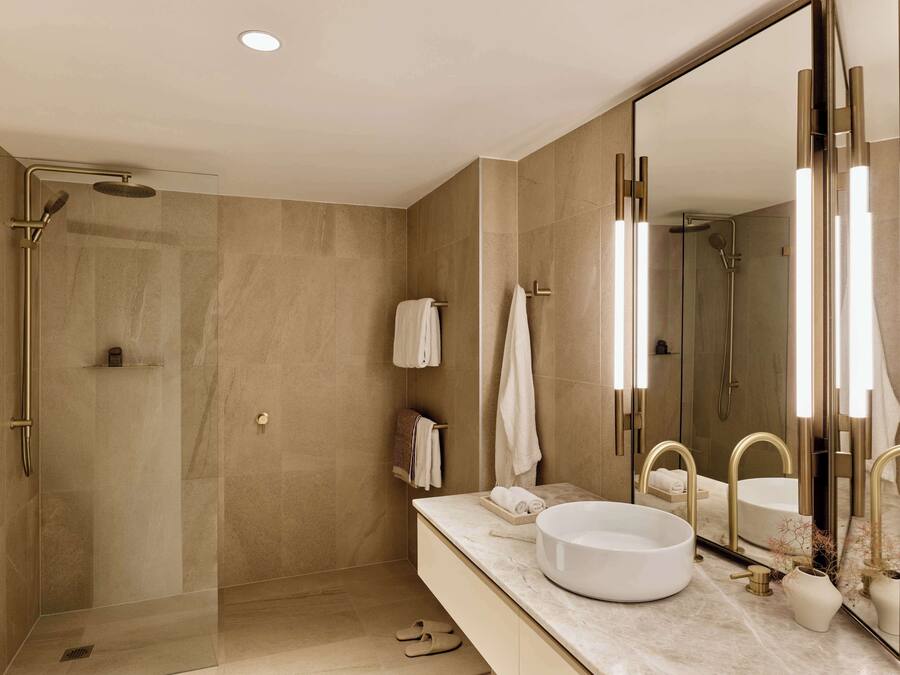 A modern bathroom with a large mirror, a round sink, and a walk-in shower.