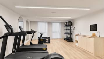 A modern gym with treadmills, a stationary bike, and weightlifting equipment.
