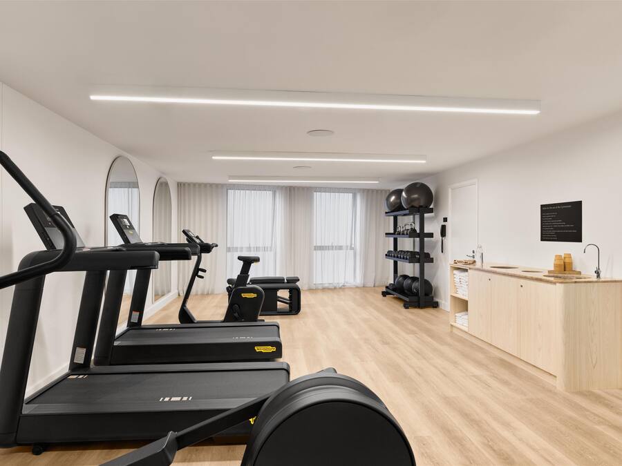 A modern gym with treadmills, a stationary bike, and weightlifting equipment.
