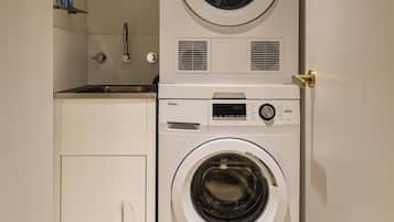 Ein kleiner Hauswirtschaftsraum mit übereinander gestapelten Waschmaschine und Trockner, einem kleinen Waschbecken und einem Schrank.