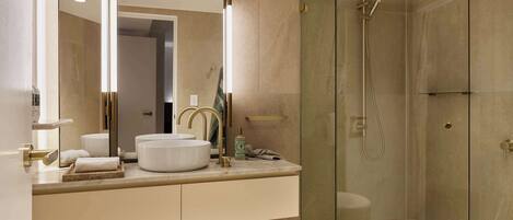 A modern bathroom with a glass-enclosed shower, a large mirror, and a white sink.