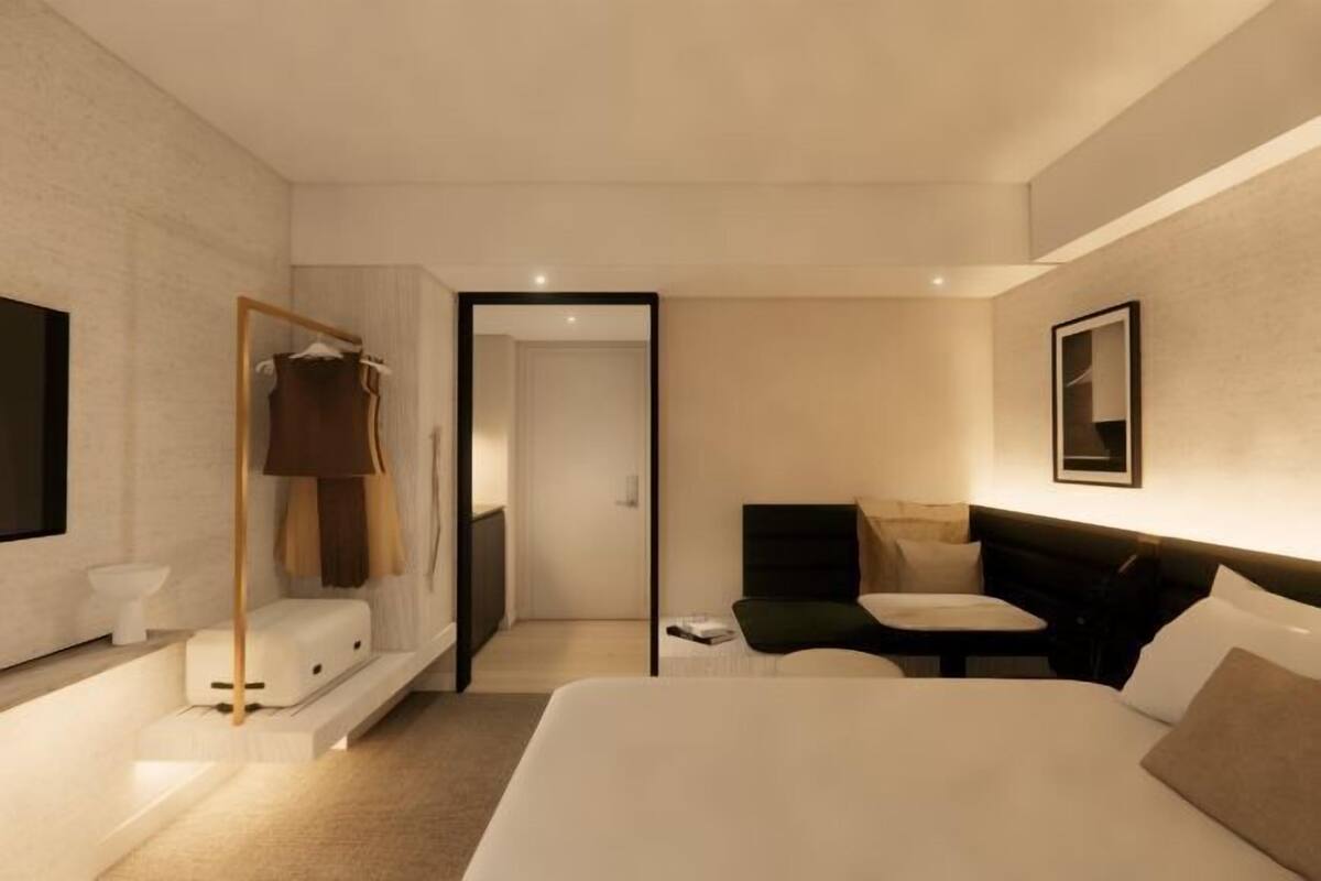 Una habitación de hotel moderna con cama, mesita de noche y espejo.