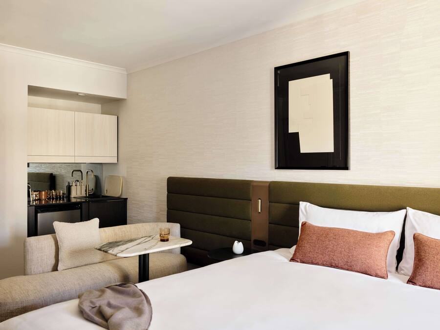 Habitación de hotel con cama, sofá, una mesita y una kitchenette.