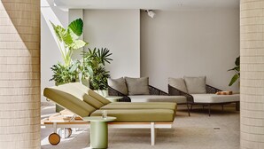 A modern indoor pool area with lounge chairs and a seating area.
