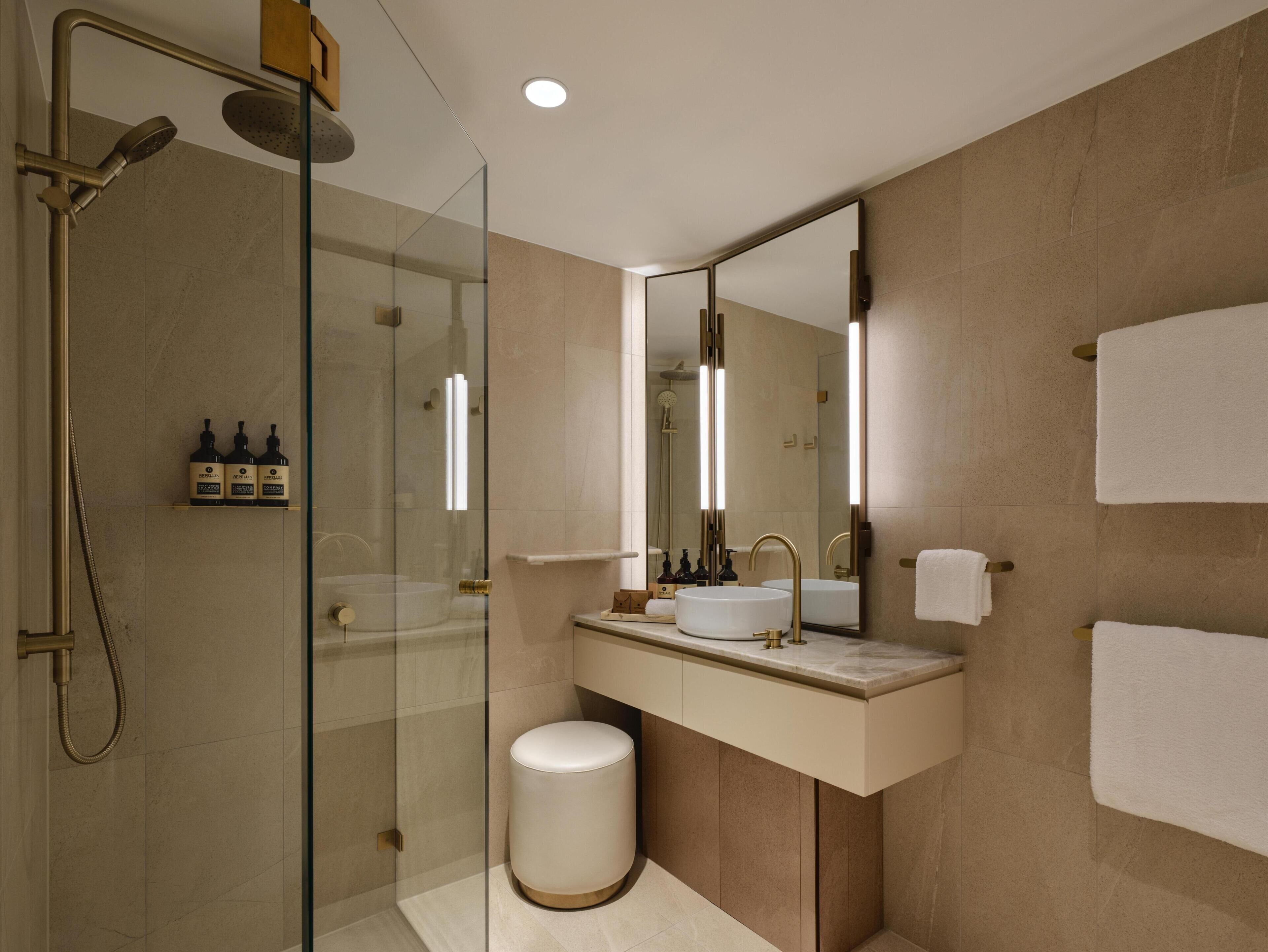 Un baño moderno con ducha de vidrio, tocador con lavabo y un espejo grande.